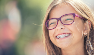 image of young girl with pink glasses and braces